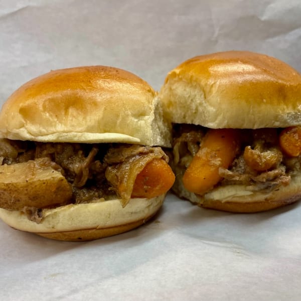 Two Doctor Dogs sliders with carrots, potatoes, and meat on a white paper background.