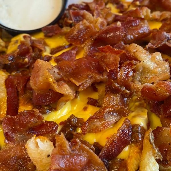 Close-up of Doctor Dogs' cheesy bacon fries, with a side of ranch dressing.